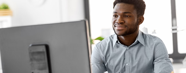 A man smiles at a computer screen.