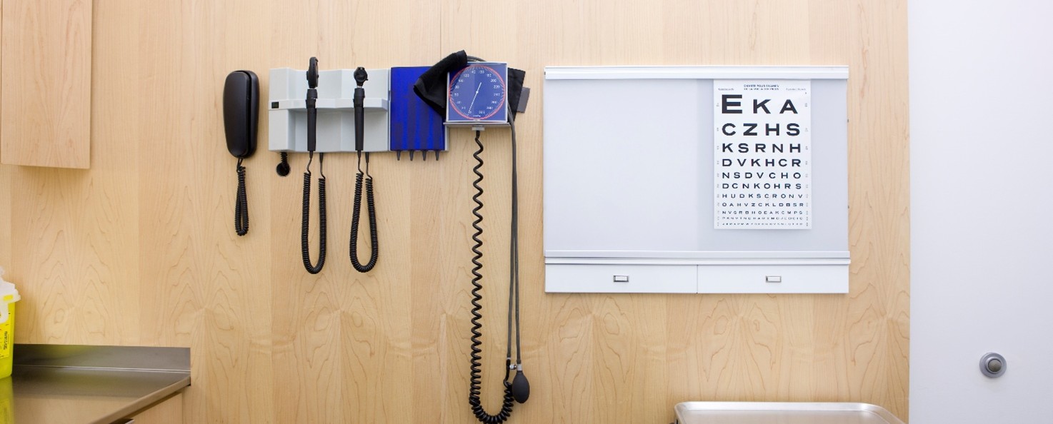 A reading chart sits to the right of medical instruments in a doctor's office.