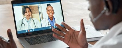 A man is engaged in a conversation with two health professionals via video call